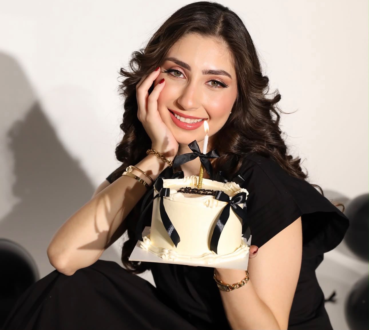 امرأة مبتسمة تحمل كيكة عيد ميلاد بشرائط سوداء